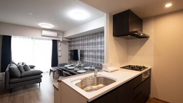 A modern kitchen with a central island, a dining area with a table and chairs, and a living area with a sofa.