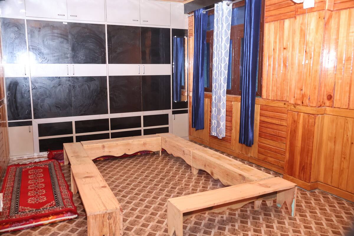 A room with a large wooden cabinet, a wooden bench, a patterned rug, and a mirror.