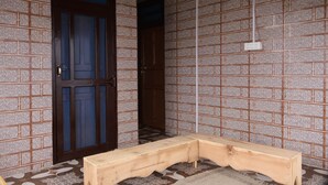 Une pièce avec un banc en bois, une porte dotée de panneaux de verre et un carrelage au motif décoratif.