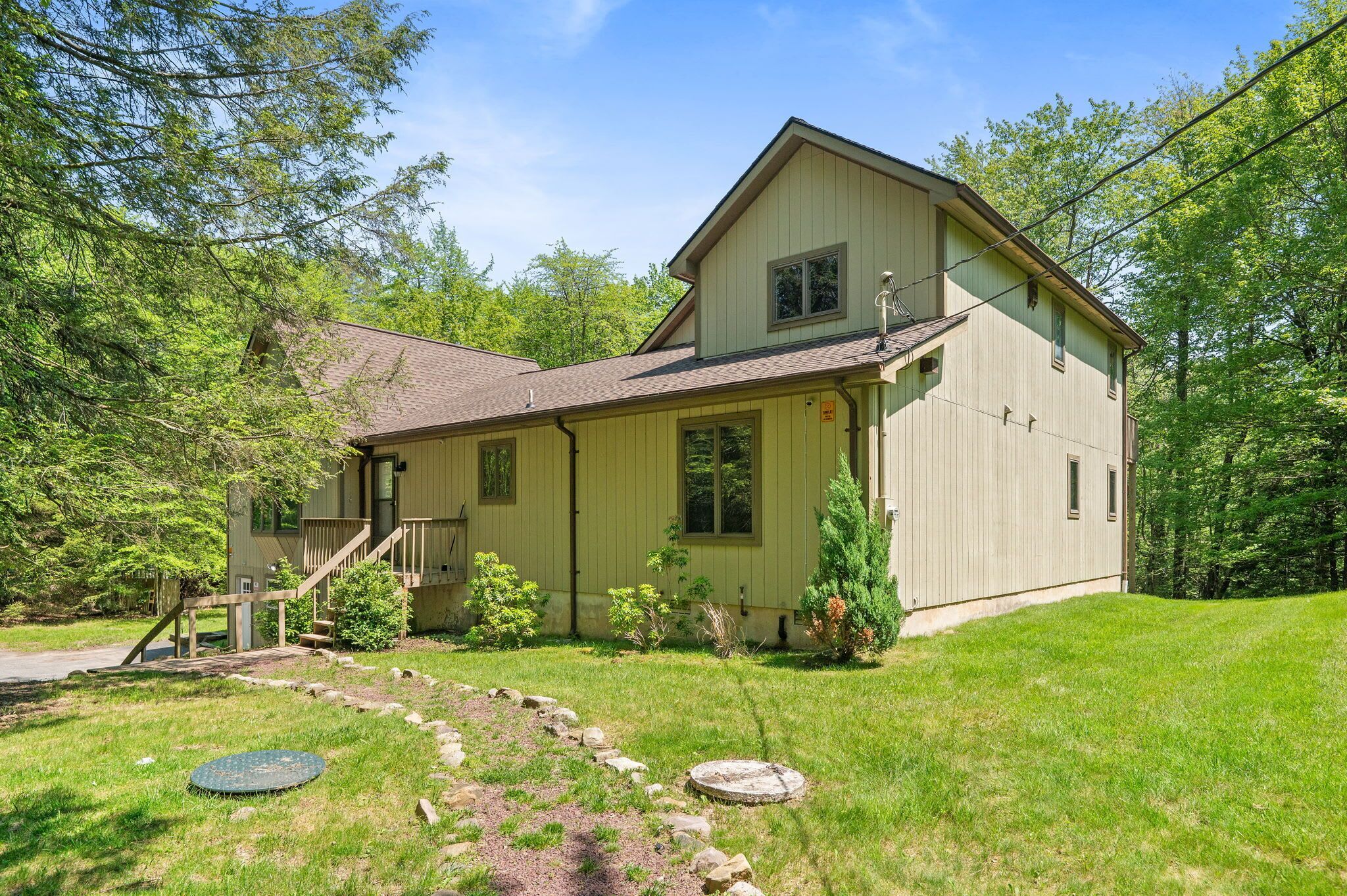 A two-story house with a front porch, a small staircase, and a well-maintained lawn.