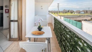 Ein Balkon mit Tisch, Stühlen und einer Topforchidee.