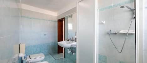 Un baño con ducha, lavabo e inodoro.