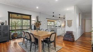 A modern kitchen with white cabinets, a wooden dining table, and black chairs.