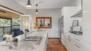 A modern kitchen with a large island, stainless steel appliances, and a wooden floor.