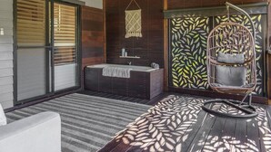 A modern bathroom with a freestanding bathtub, a ceiling fan, and a decorative leaf-patterned wall.