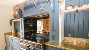 A kitchen with dark blue cabinetry, a black stove, and a wooden countertop. - Arbour House Farm Bungalow (Durham)