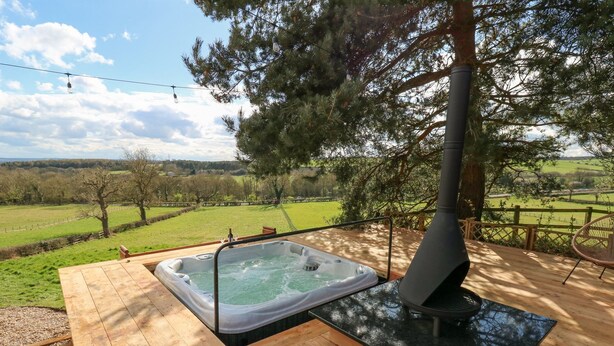 A hot tub on a wooden deck with a view of a green field and trees. - Arbour House Farm Bungalow (Durham)
