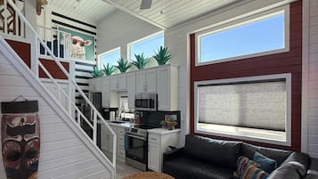 A modern kitchen with white cabinets, a black countertop, and a ceiling fan.