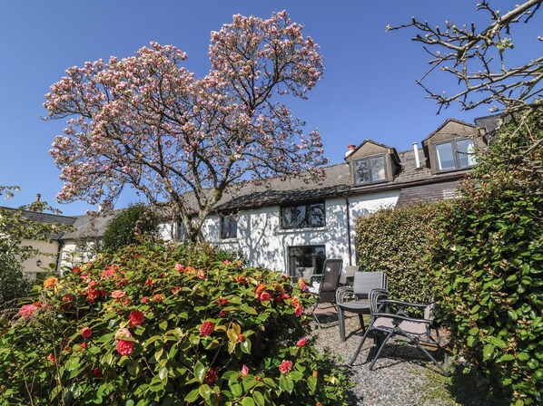 A house with a garden, a patio with chairs, and a tree with pink blossoms. - Magnolia View (Barnstaple)