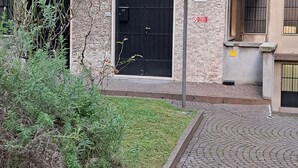 Ein Gebäude mit einem schwarzen Tor, einem kleinen Garten und einem Kopfsteinpflasterweg.
