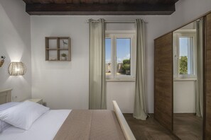 Une chambre à coucher comprenant un lit, une table de chevet, une étagère avec des objets décoratifs, une fenêtre avec des rideaux et une vue sur l’extérieur.