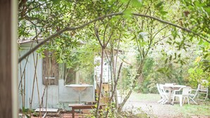 A rustic outdoor area with a wooden table and chairs, a small shed, and a garden path.