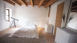 A bedroom with a bed, a telescope, a dresser, and a window.