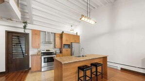 A modern kitchen with wooden cabinets, stainless steel appliances, and a central island with stools.