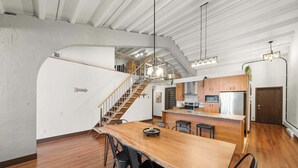 A spacious kitchen with a wooden table, chairs, and a staircase leading to an upper level.
