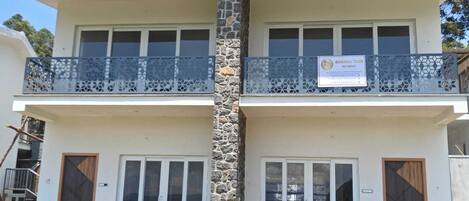Un edificio de dos pisos con una columna de piedra, balcones con barandillas de metal y un letrero que indica que es un lugar de retiro para personas mayores.