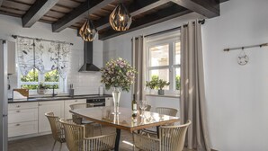 A modern kitchen with a dining area, featuring a glass table, wicker chairs, and pendant lighting. - Villa Stina Zadarvillas (Sukosan)