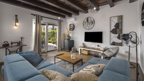 A living room with a sofa, a coffee table, a TV, and a fan. There is a window with curtains and a door leading outside. - Villa Stina Zadarvillas (Sukosan)