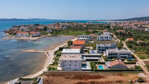 An aerial view of a coastal residential area with houses, a beach, and a clear blue sea. - Villa Stina Zadarvillas (Sukosan)