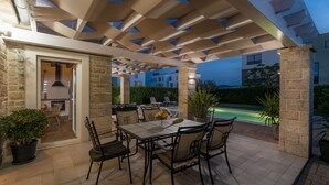 An outdoor patio with a table and chairs, a pool in the background, and a stone wall. - Villa Stina Zadarvillas (Sukosan)