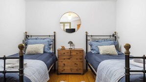 A bedroom with two beds, a dresser, a mirror, and a wooden floor. - Apartment Dei Fiori 1 (Rovinj)