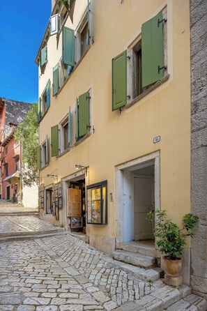A cobblestone street with a building featuring green shutters and a visible door number. - Apartment Dei Fiori 2 (Rovinj)