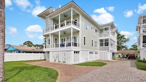 A multi-story house with a covered front porch, a garage, and a driveway. - Rooftop Deck, Soaring Views & Steps to Tybee’s Best Beaches by Tybee Cottages (Tybee Island)