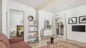 A living room with a sofa, a coffee table, a bookshelf, a TV, and a door leading to another room. - Secret Steps Apartment (Rovinj)