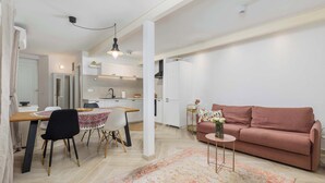 A modern living room with a sofa, a dining table with chairs, a kitchen area, and a hallway. - Secret Steps Apartment (Rovinj)