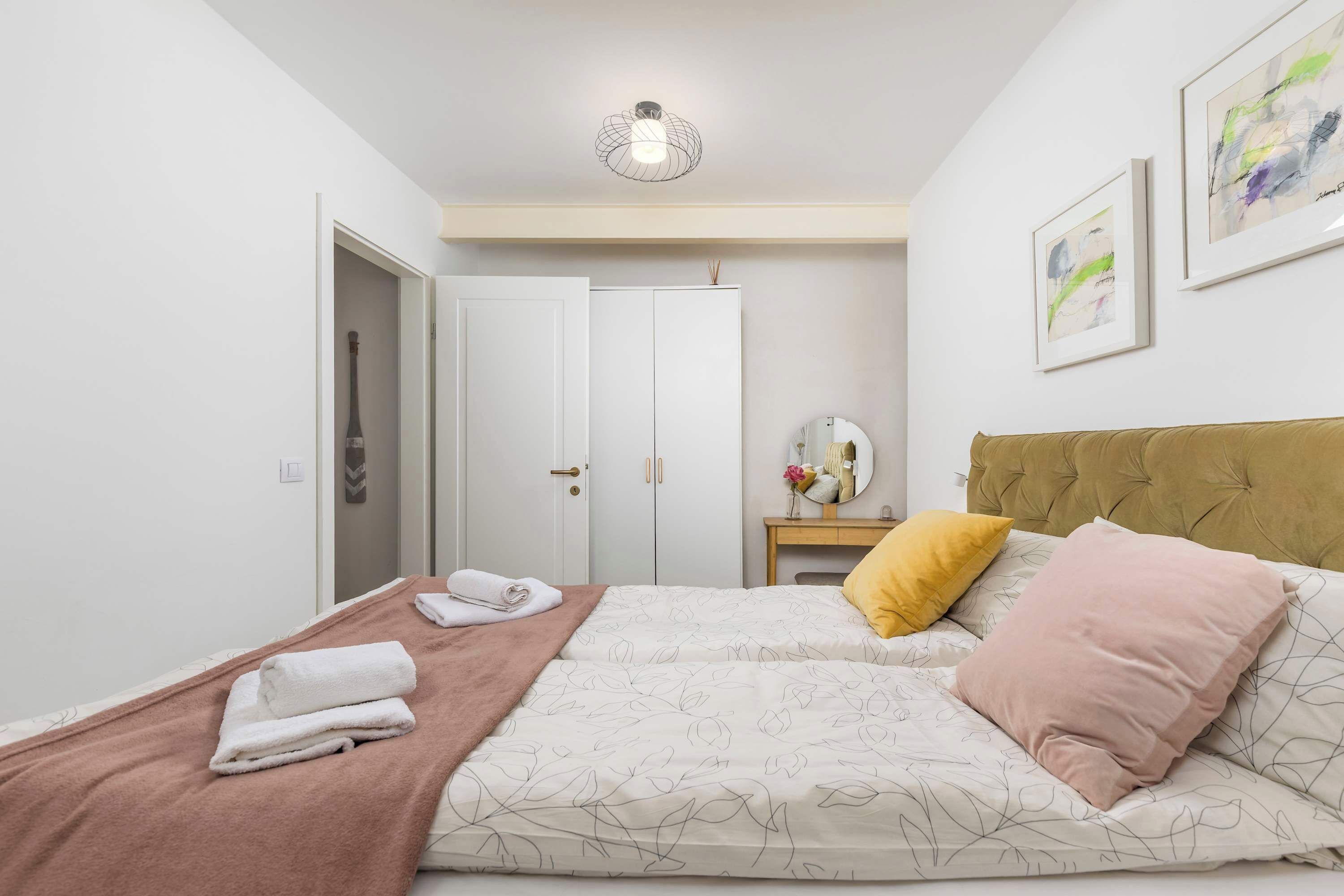 Een slaapkamer met twee bedden, een nachtkastje, een spiegel en een deur naar een andere kamer.