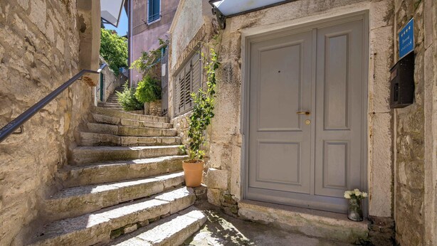 A narrow stone staircase leading to a door with a sign indicating a restaurant. - Secret Steps Apartment (Rovinj)