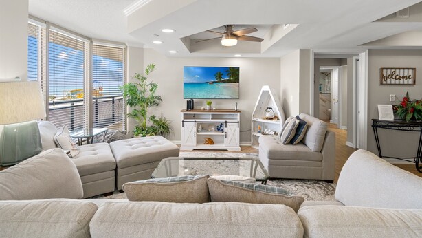A living room with a sectional sofa, a coffee table, a TV, and a ceiling fan. - Brighton 107 3 Br in Kingston Beach, Pool (Myrtle Beach)
