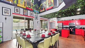 A modern kitchen with red cabinets, a stainless steel refrigerator, and a microwave. - PROMO Villains Lair 8 BR Home, Private Pool - by Blue Sky Villas (Kissimmee)