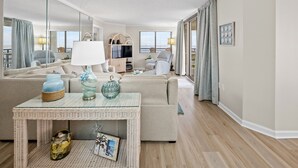 Ein modernes Wohnzimmer mit einer Couch, einem Glastisch und einem Fernseher.