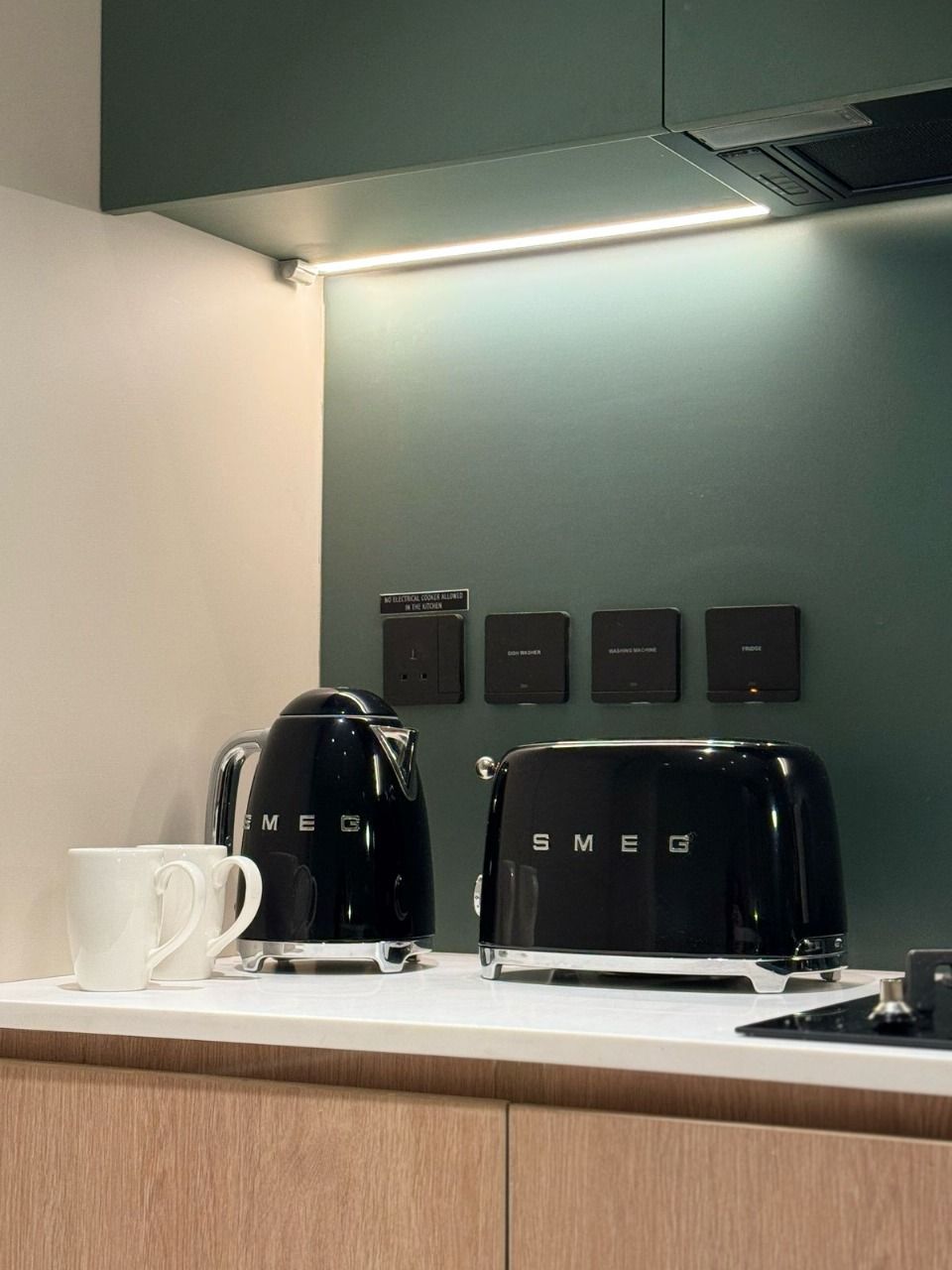 A kitchen with two black coffee makers labeled 'SMEG' and a white mug on the counter.