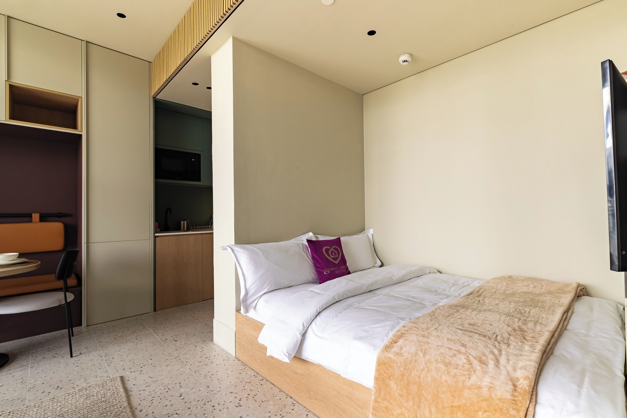 A modern bedroom with a bed, a desk, and a TV.
