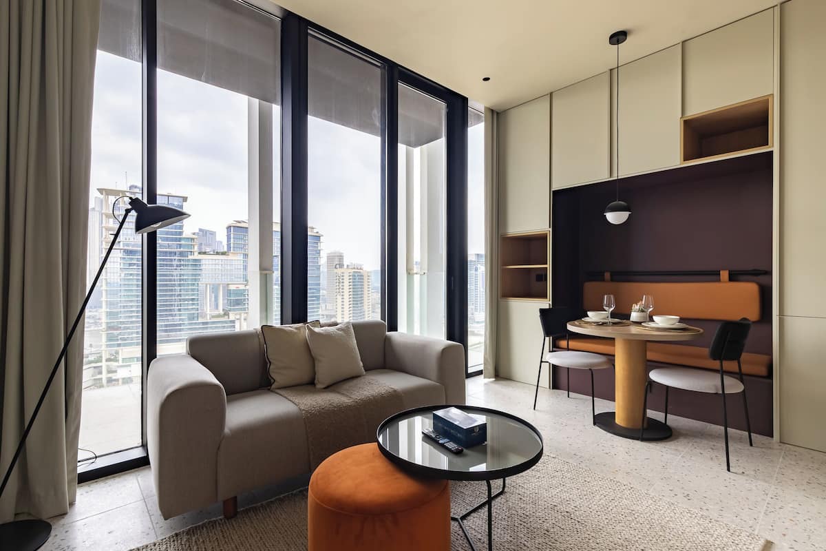 A modern hotel room with a sofa, a round table, and a dining area.