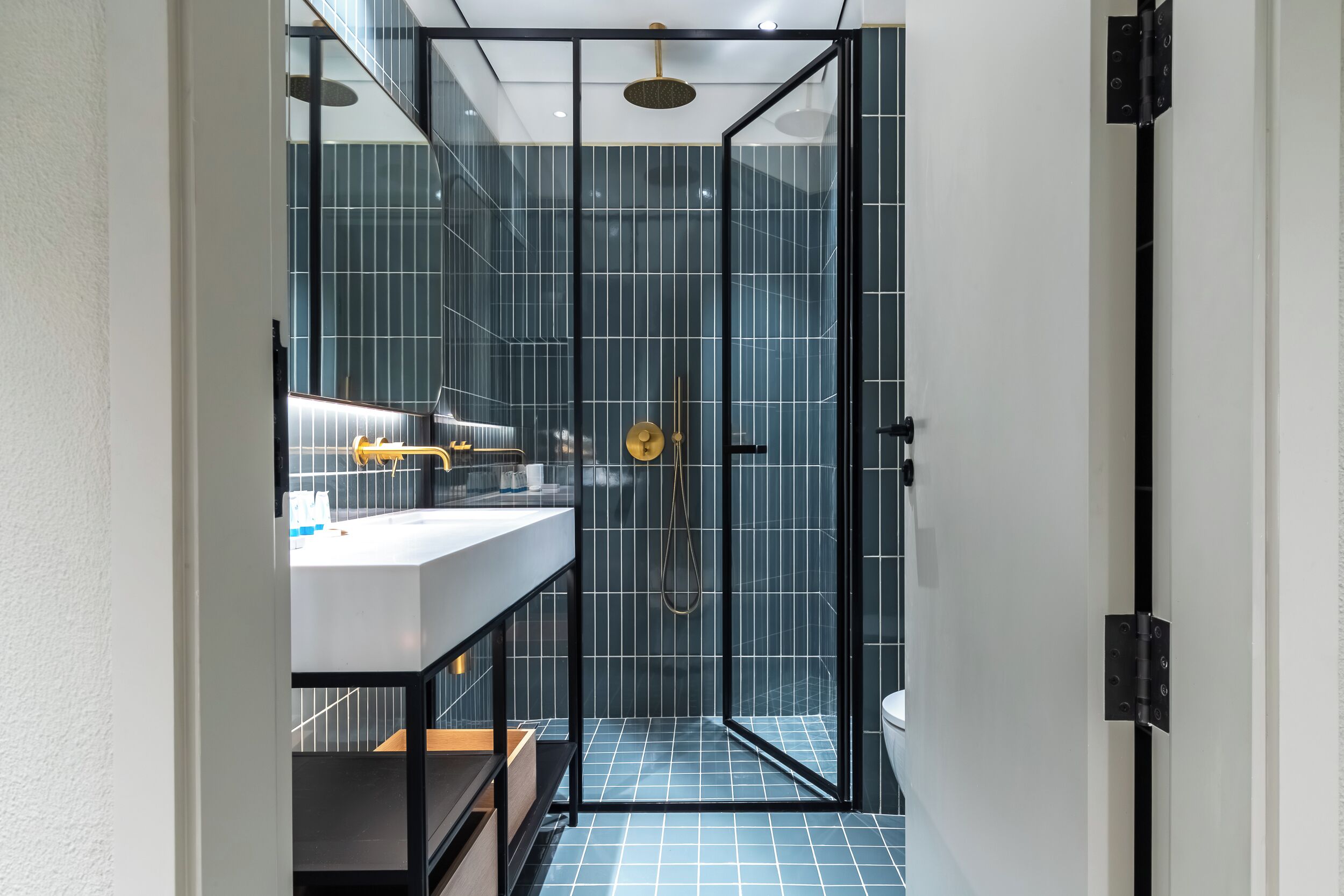 Une salle de bain moderne avec une douche à parois de verre, un lavabo blanc et un miroir à cadre noir.