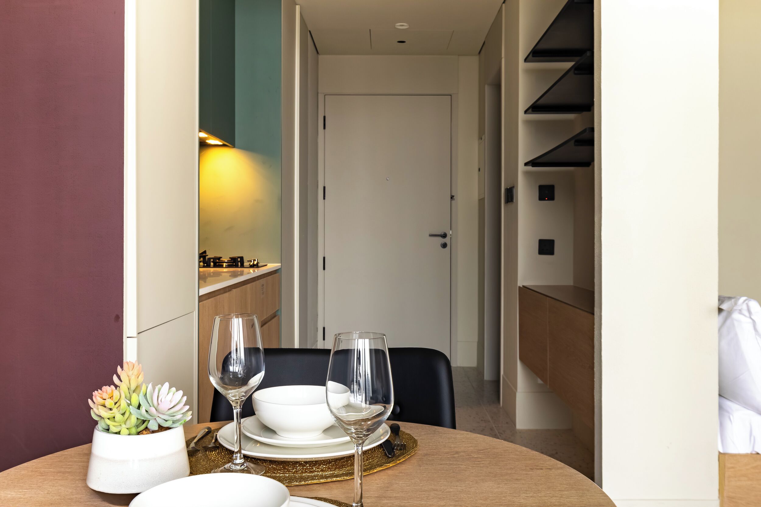 A dining area with a table set for two, a potted succulent, and a bowl of white flowers.