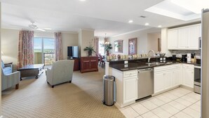 A spacious living area with a sofa, a dining table, and a kitchen with white cabinets and a granite countertop. - Royale Palms 1405 3 Br Oceanview in Kingston, Pool (Myrtle Beach)