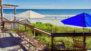 A wooden deck with outdoor seating and umbrellas overlooking a beach. - Royale Palms 1405 3 Br Oceanview in Kingston, Pool (Myrtle Beach)
