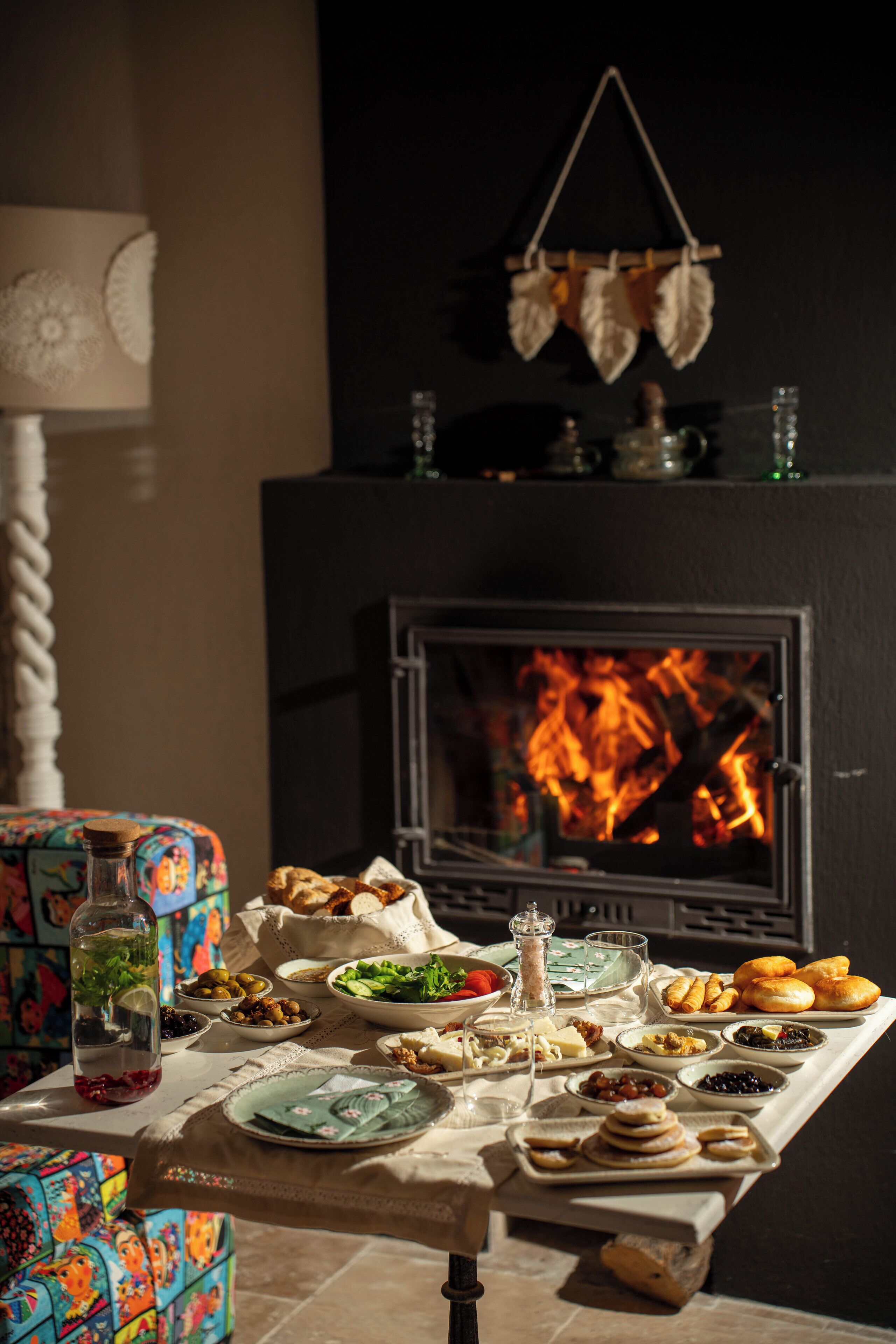 Una mesa de comedor preparada con diversos platos y una chimenea al fondo.