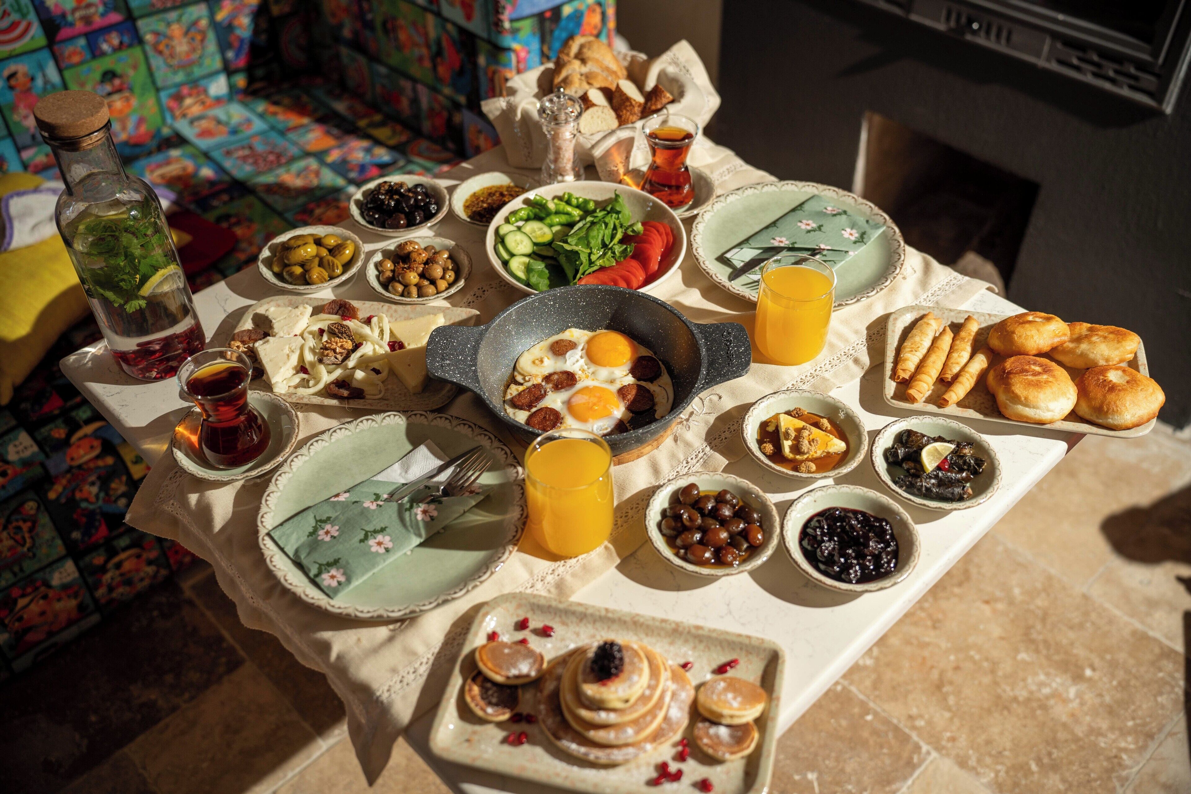 A breakfast table with various dishes, including eggs, bread, and fruit.
