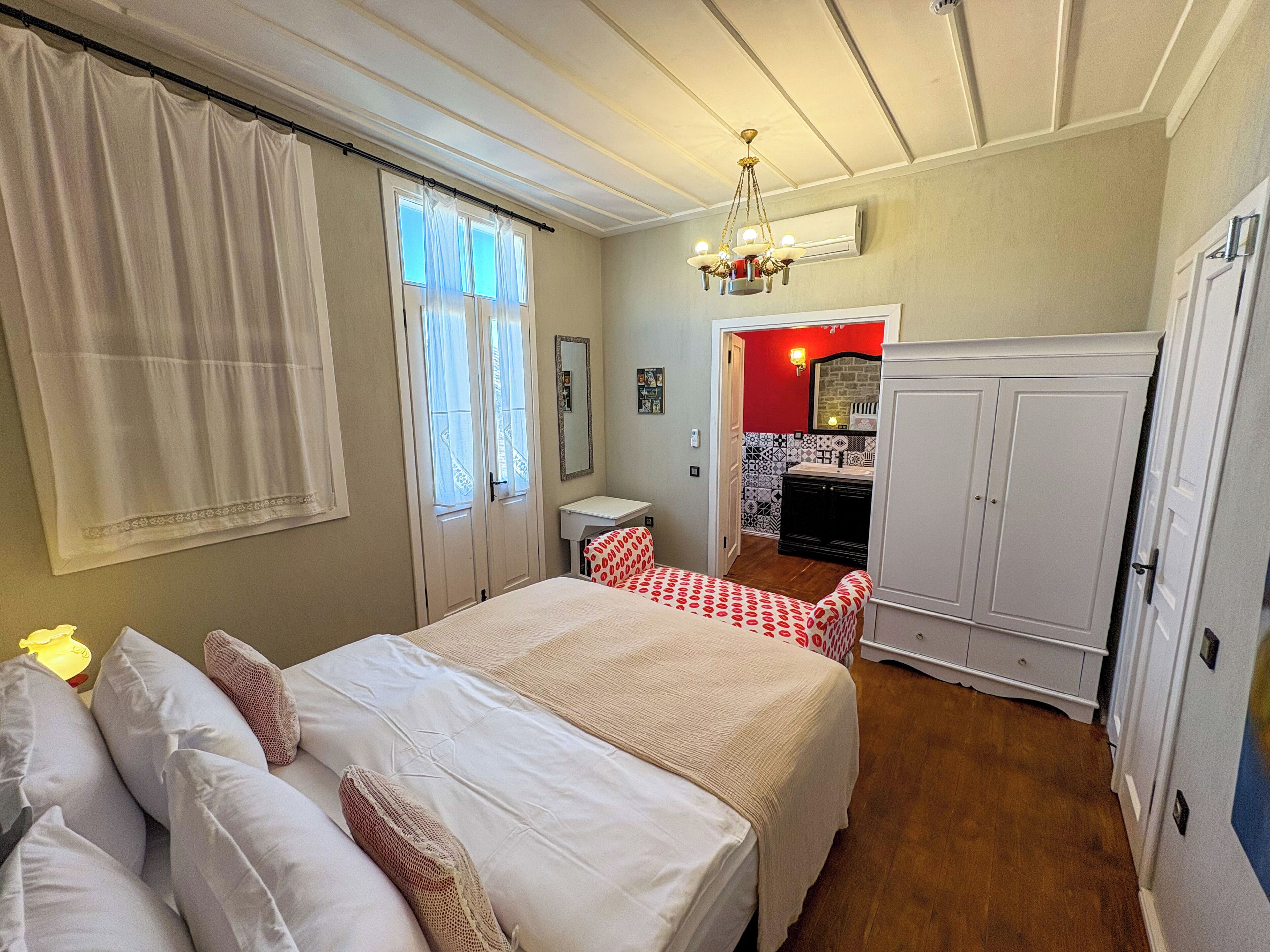 Une chambre à coucher comprenant un lit, une table de chevet, une armoire et une salle de bain visible à travers une porte ouverte.