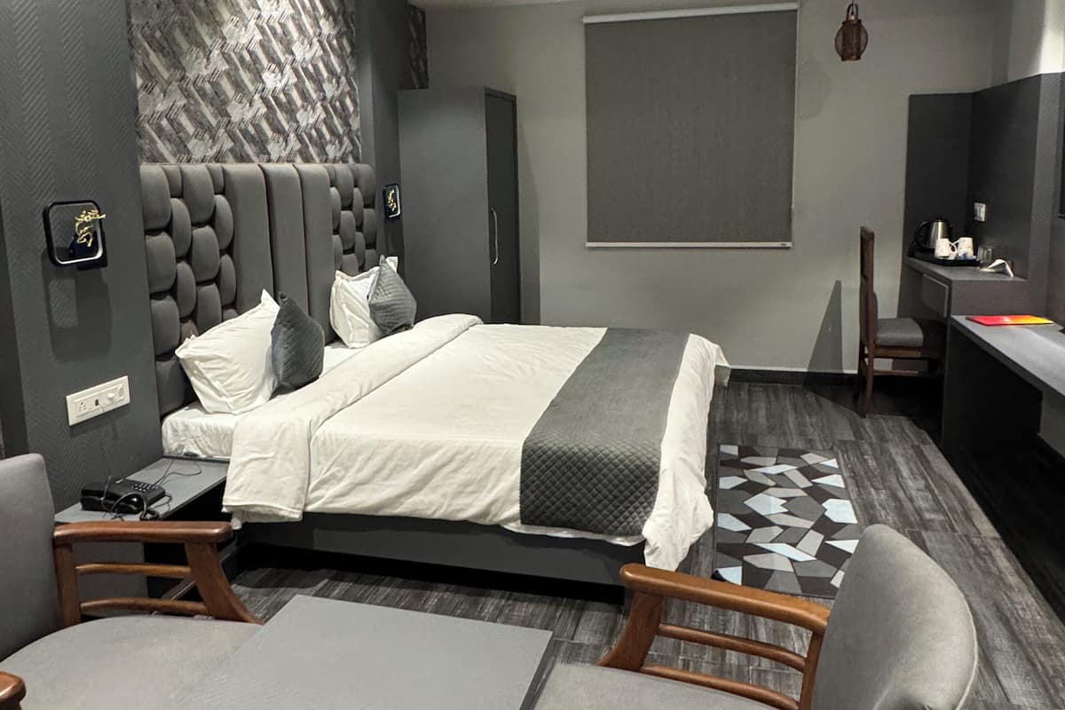 A modern bedroom with a bed, bedside tables, a desk, and a chair.