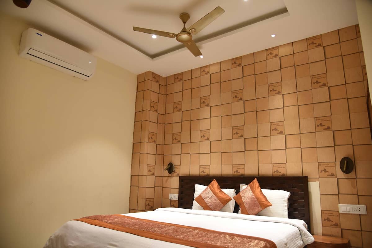 A hotel room with a bed, a ceiling fan, an air conditioning unit, and a wall with a patterned design.