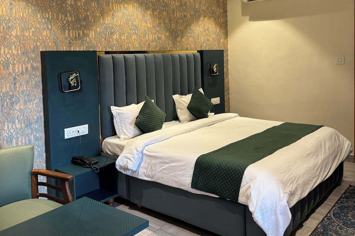A modern hotel room with a large bed, a desk, and a ceiling fan.