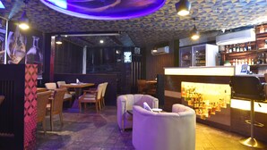 Zona de bar con asientos, una barra con botellas y un techo estampado.