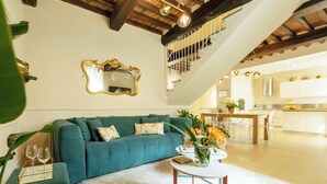 A modern living room with a teal sofa, a coffee table with a vase of flowers, and a staircase leading to an upper level. - Dimora Paolina charming villa with secret garden, in the historical center of Lucca (Lucca)