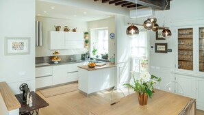 A modern kitchen with white cabinetry, a wooden island, and a dining area with a table and chairs. - Dimora Paolina charming villa with secret garden, in the historical center of Lucca (Lucca)